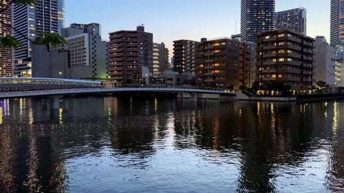 Cityscape reflected in a river during twilight with illuminated buildings