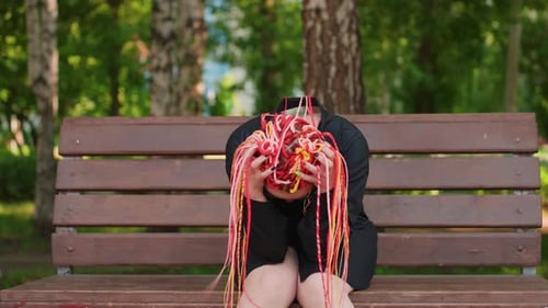 Colorida tristeza capturó a una mujer solitaria con un cabello vibrante en el banco del parque, expresivo retrato de