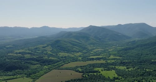 Paysage relaxant de prairies, de platanes, de forêts, de montagnes et de villages à peine visibles