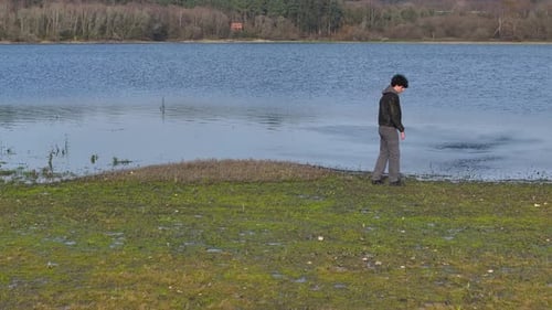 Young Man Throwing Rocks To The Lake - Drone Shot