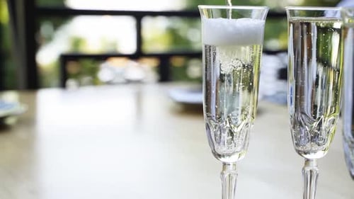 Champagne Pouring into Crystal Flutes on Wooden Table