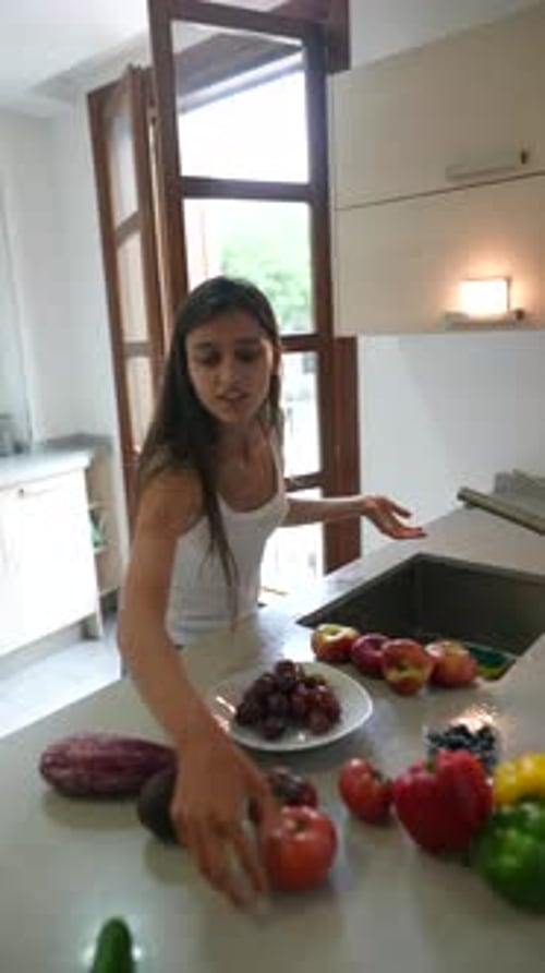 In a Modern Kitchen a Young Woman Can Be Observed Washing a Variety of Fresh Fruits