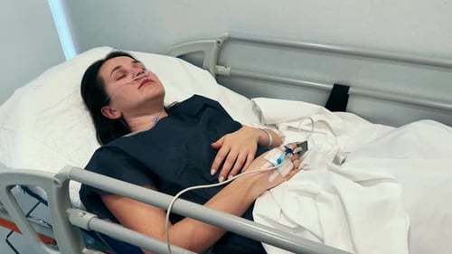 Patient Lies in Bed in the Hospital with Intravenous Drip in the Hand After Surgery Healthcare and