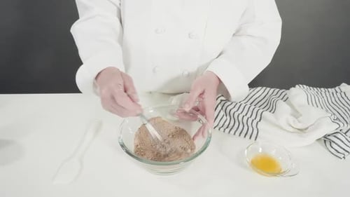 Cook Mixing Ingredients with Whisk in Glass Bowl