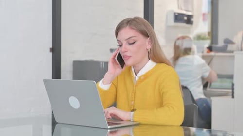 Woman Working on Laptop and Talking on Phone