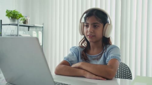 Girl Using Laptop Wearing Headphones at Home