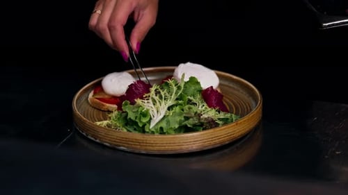 Close Up in a Professional Kitchen on Clean Metal Table a Woman Chef Collects a Salad with Fresh