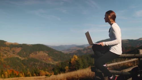 Woman working with a laptop in the mountains