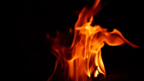Zoomed in video of yellow flame from burning fire in darkness