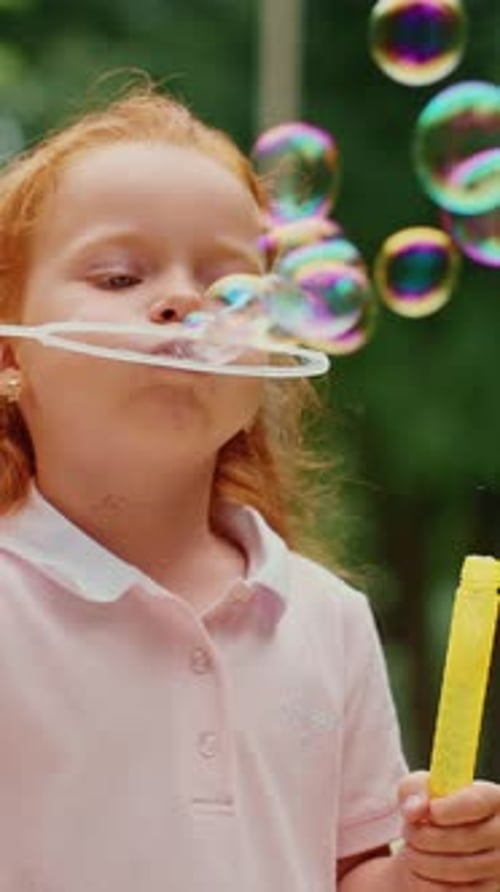 Child Blowing Bubbles in Sunny Park Surrounded By Trees