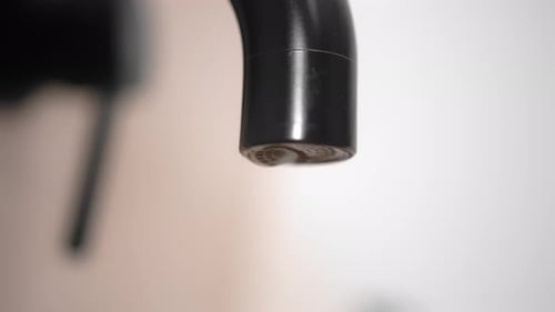 Drop of pure water dripping from modern tap. Selective focus.