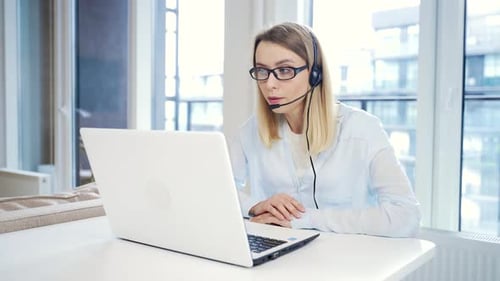 Woman with Headset at Laptop Video Conferencing