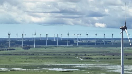 Cinematic 7x telephoto aerial panorama of massive wind farm. ESG concept.