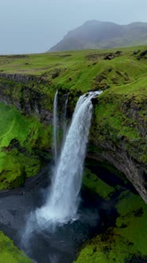 Waterfall Flowing Over Green Cliffs Aerial Shot