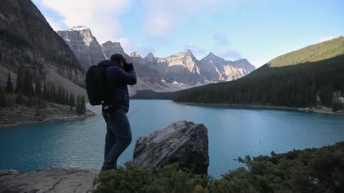 Tourist Photographer Capturing Scenic View With Mountainscape At Background In Moraine Lake, Alberta
