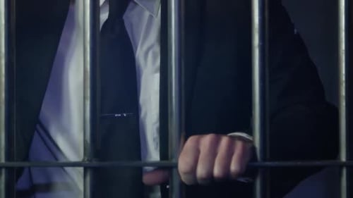 White Collar Crime - Man holding bars of prison cell in suit HD