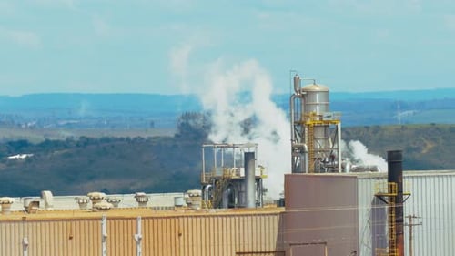 Steam, smoke and gas pollutants emissions coming from a factory smokestack in slow motion