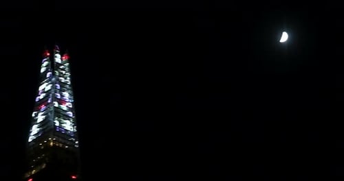 Changing lights in front of the moon on The Shard after Christmas 2022, London, United KIngdom