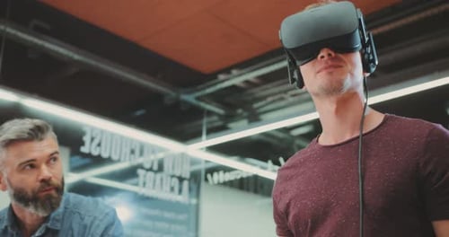 One Man in Virtual Reality Glasses the Second Man Uses a Laptop in the Office Contemporary Design
