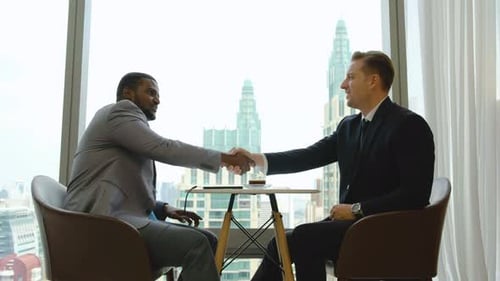 Two multiethnic professional employees, colleagues having friendly informal talk in company office