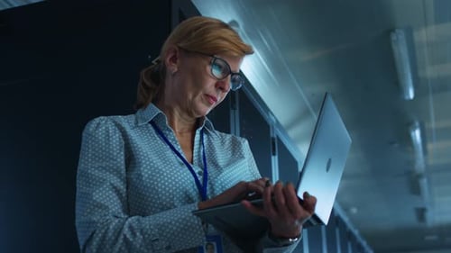 In Data Center: Portrait of Professional Female IT Specialist Using Laptop, Doing Maintenance and D