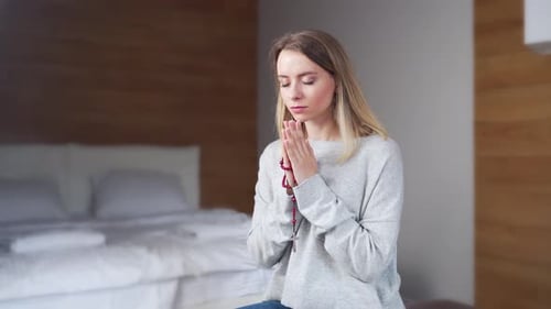 Woman with Rosary Praying in a Bedroom