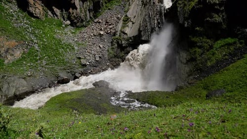 Majestic Waterfall Cascading Over Rocky Cliffs Surrounded By Lush Greenery and Vibrant Wildflowers