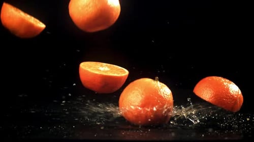Rebanadas de mandarinas frescas que caen sobre fondo negro filmadas con una cámara de alta velocidad a 1000 fps