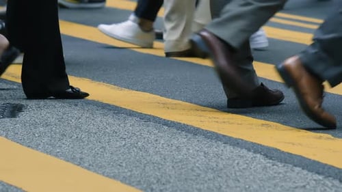 Vista aproximada dos pés das pessoas na movimentada faixa de pedestres. Conceito de viagens para pessoas ocupadas. Câmera lenta.