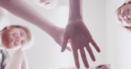 4k video footage of a group of young businesspeople joining hands in solidarity in a modern office