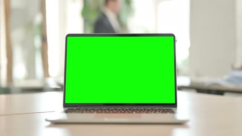 Laptop with Green Screen on Desk in Office