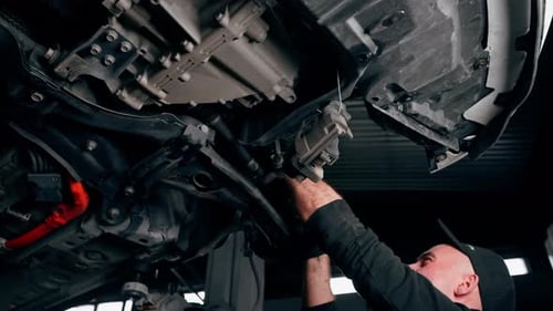 Vertical Video an Auto Mechanic at a Service Station is Trying to Remove the Base on Which the Wheel