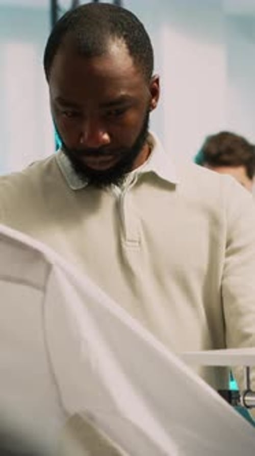 Man Inspects Shirt in a Retail Workplace