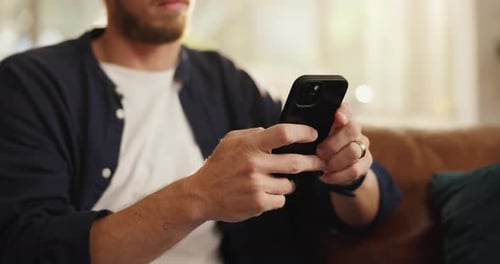 Man Using a Mobile Phone Sitting on Sofa