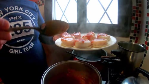 Woman putting tomato sauce with a spoon, Italian pasta (Sorrentinos) in the kitchen