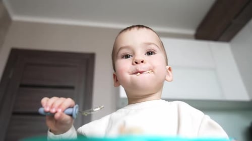Adorable Infant Eating Lunch Indoors with Spoon