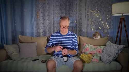 Man Relaxes on Couch with Beer and Chips