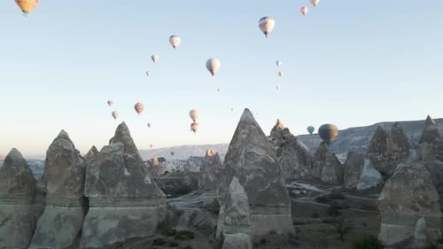 Aerial view of cave homes with hot air balloons in Cappadocia, Turkey.