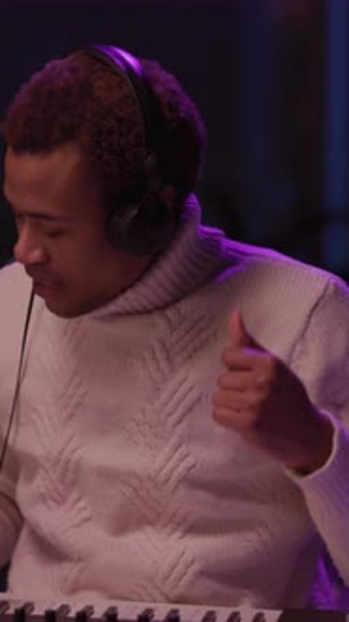 Man Sings Into Microphone Wearing Headphones in Studio