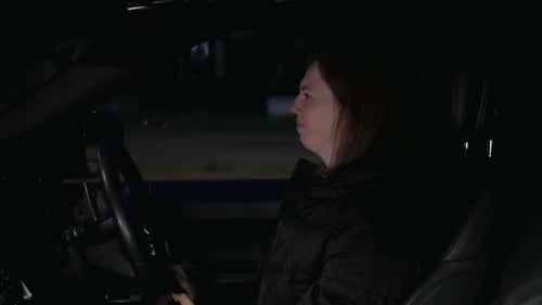 Frustrated female driver stuck in traffic jam late at night. The girl is looking at her watch in fru