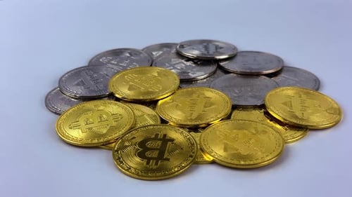 Silver and gold bitcoin rotate on a white surface