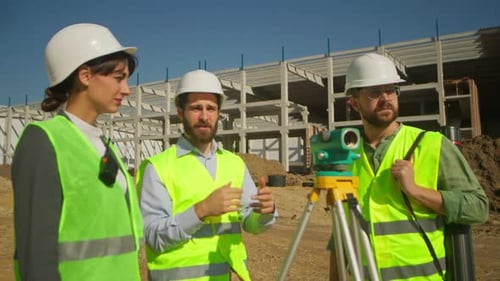 Two Caucasian Men and Woman in White Protective Helmets and Yellow Vests Discussing Work Processes