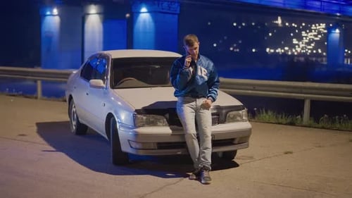 Man By White Car Under Glowing Bridge Contemplative Figure Leaning on Sedan Beneath Luminous Bridge