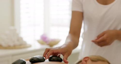 A young woman getting a hot stone treatment at a day spa