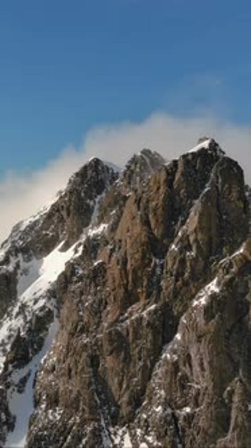 Snowy Mountain Peak With Fast Clouds In The Blue Sky. British Columbia, Canada.