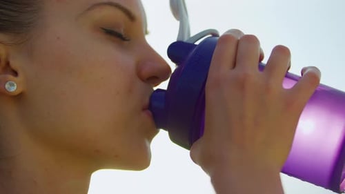 Woman Drinks Refreshing Water From Bottle Outdoors