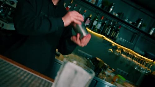 The process of making a cocktail in a bar A bartender mixes the ingredients of an alcoholic cocktail