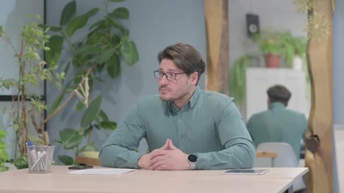 Mature Man Thinks at His Desk in Office