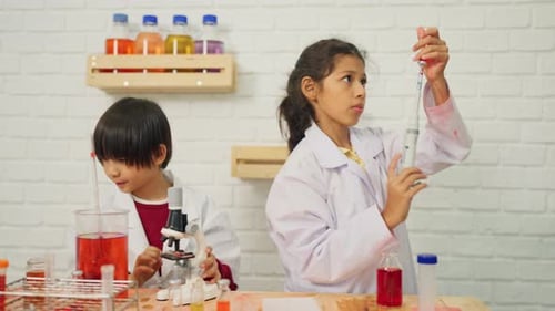 Front view of young scientist boy and girl enjoy to learn and practice to do the experiment school