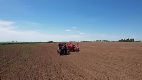 Aerial view of red tractor plowing field, Bulgaria.